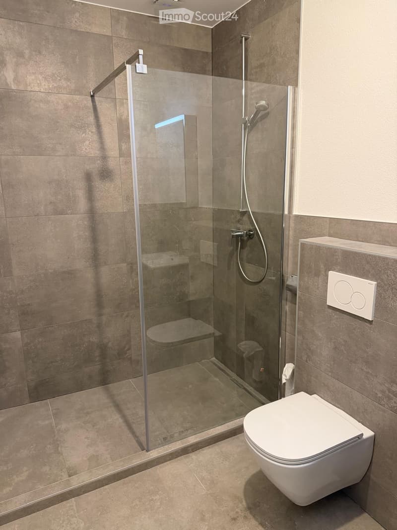 Bathroom. Modern bathroom with a white toilet, glass-enclosed shower, and beige tiled walls and floor.