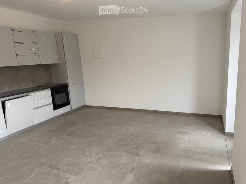 Unfurnished Room. Empty kitchen with light grey cabinets, a black countertop, and a tiled floor. No appliances or furniture are present.