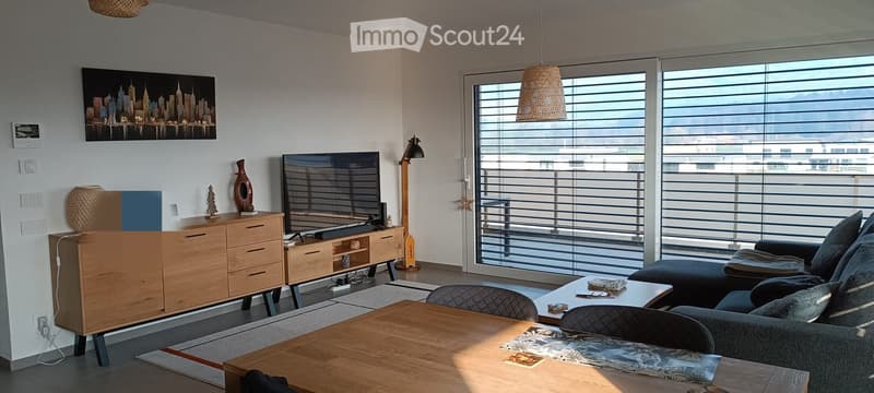 modern living room with large windows, wooden furniture, flat screen TV, couch, table, and decorative items