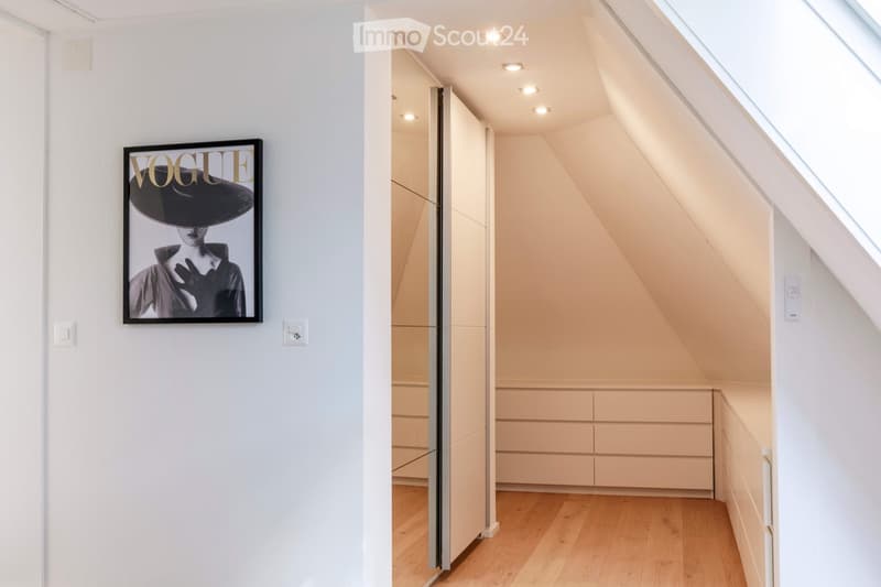 Modern hallway with white walls, wooden flooring, built-in storage units, and a large framed poster on the wall.