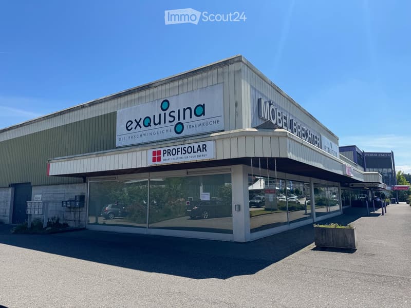 Commercial building with signage for "exquisina" and "PROFISOLAR" visible, large glass windows, and a covered entrance area.