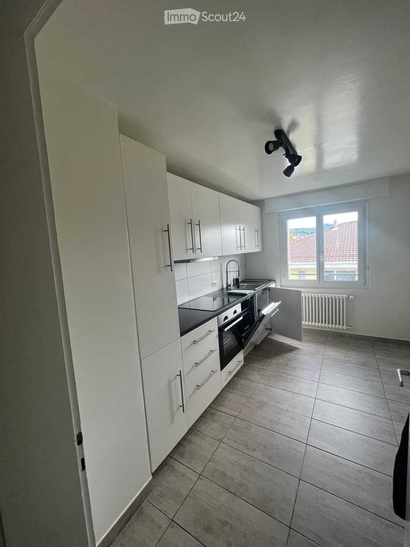 Empty kitchen with white cabinets, stainless steel sink, and tiled floor. No appliances or furniture present.