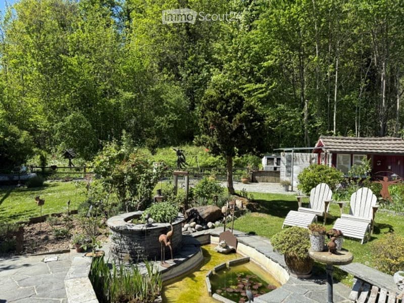 Garden / Outdoor Area. A well-maintained garden with a stone fountain, a small pond, decorative statues, and several lounge chairs arranged on a stone patio.