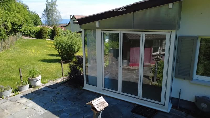 Garden / Outdoor Area. Garden area with a paved patio, glass sliding doors leading to a room, potted plants, and a small birdhouse on the ground.