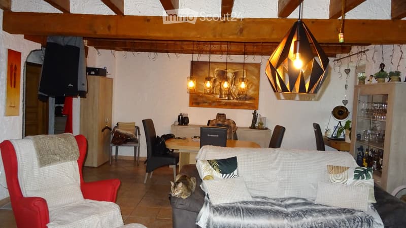 Main living area with a dining table, chairs, and couches, with a cat and decorative items.