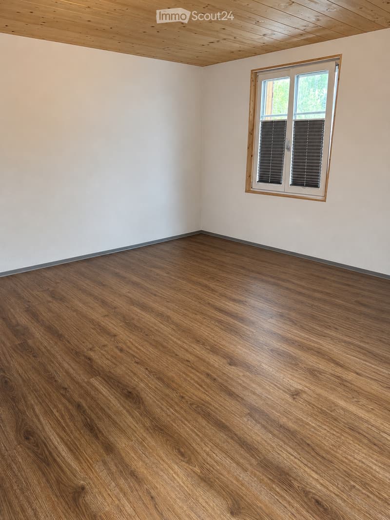 Empty room with wooden flooring and white walls, featuring a single window with blinds.