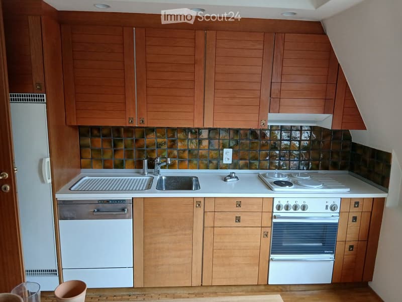 Compact kitchen with wooden cabinets, white appliances, and a tiled backsplash. Features a sink, stove, oven, and dishwasher.
