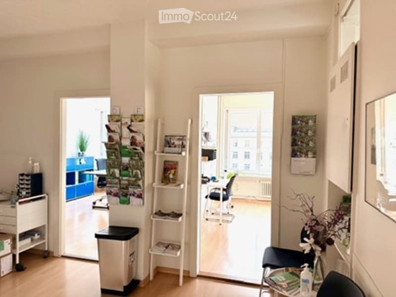 Light wood floor, white walls, open doorway, small desk, cabinets, flowers, mirror