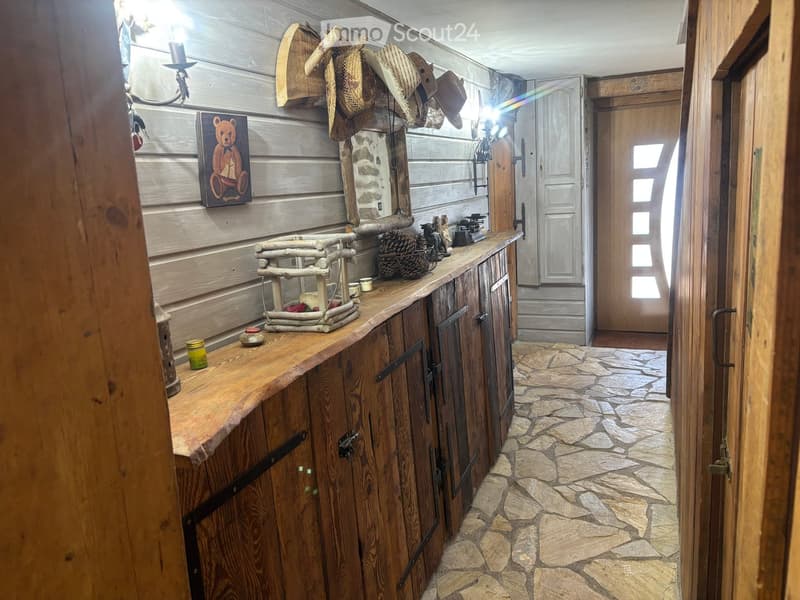 Corridor / Hallway. Wooden hallway with rustic decor, including wooden cabinets, hats on the wall, and a stone-tiled floor.