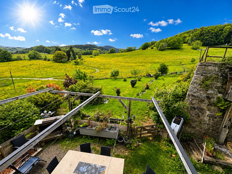 Balcony / Terrace. Balcony with wooden railing, outdoor table, chairs, and lush green landscape view.