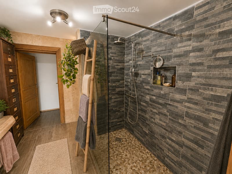 Bathroom. Modern bathroom with a glass-enclosed shower, dark stone tiles, wooden cabinet, and bamboo towel rack. Features a built-in shelf with toiletries and a small plant on the windowsill.