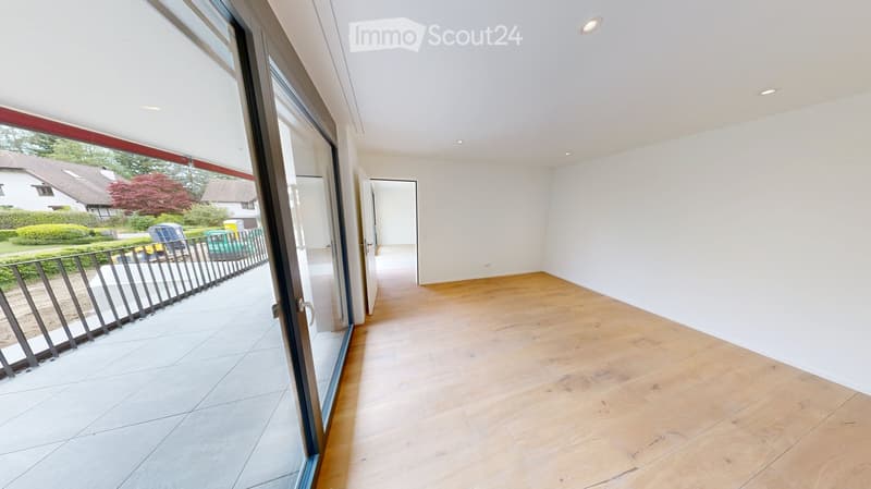 Empty room with wooden flooring, white walls, and large sliding glass doors leading to a tiled balcony area.