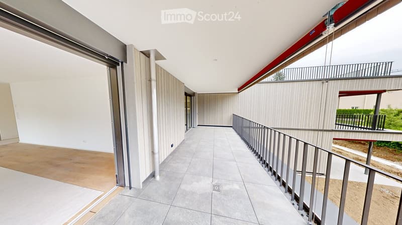 Modern hallway with tiled flooring, white walls, and metal railings leading to a balcony area.