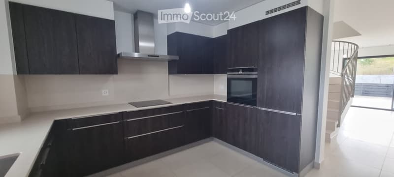 Modern kitchen with dark wood cabinets, stainless steel appliances, and a balcony view.