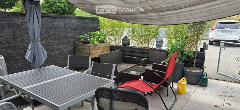 Outdoor seating area with a table, chairs, and a canopy. Potted plants and a statue are also present.