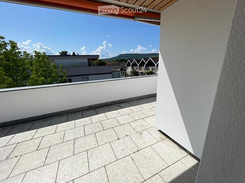 Balcony with white tiled flooring, white railing, and a view of surrounding buildings and greenery.
