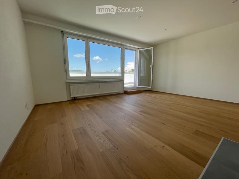 Empty room with wooden flooring, large windows, and a radiator under the windows.