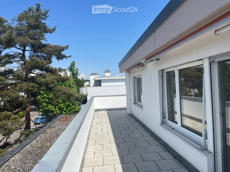 Balcony with tiled floor, white walls, large windows, and a view of greenery and a parked car.