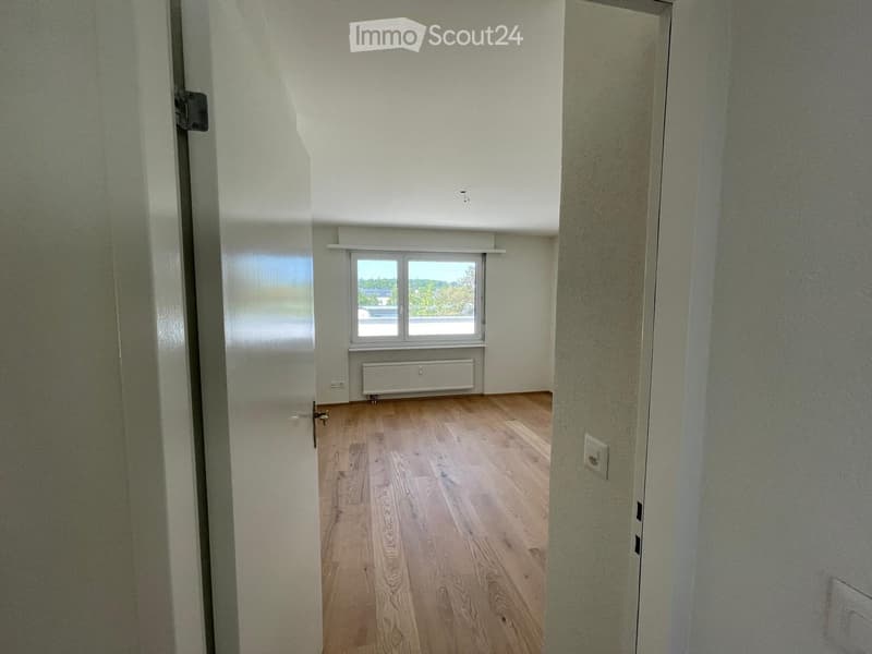 Empty room with wooden flooring, white walls, a window with blinds, and a radiator below it.