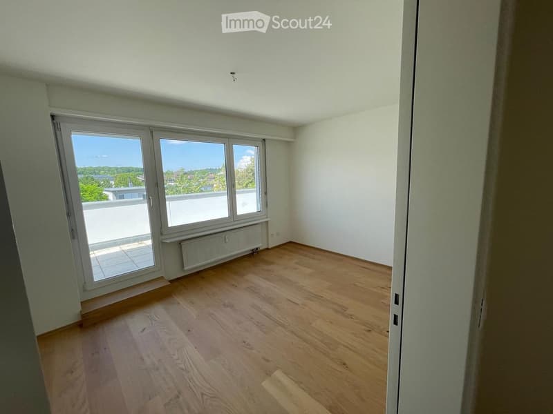 Empty room with wooden flooring, white walls, large windows, and a radiator. No furniture or equipment present.