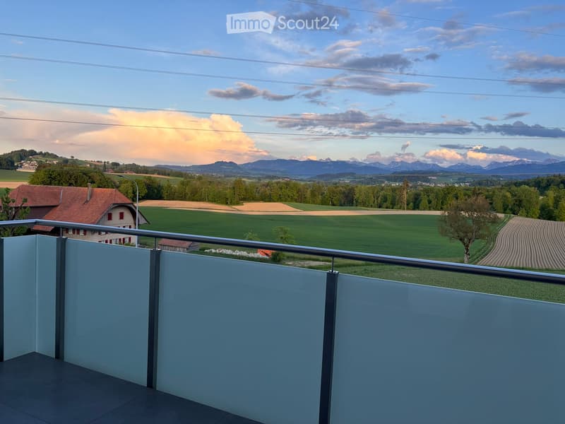 Balcony / Terrace. Balcony with a modern railing, overlooking a scenic countryside with green fields, a house, and distant mountains under a partly cloudy sky.