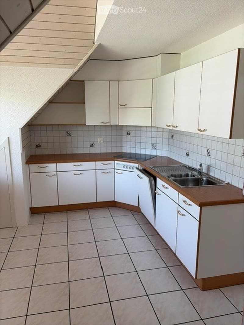 Modern kitchen with white cabinets, wooden countertops, tiled floor, and built-in appliances including an oven and sink.