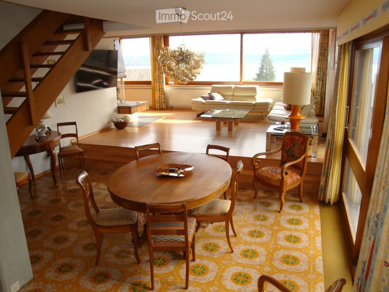 living room with dining area, wooden floor, large windows, wooden table and chairs, couch, lamp, TV