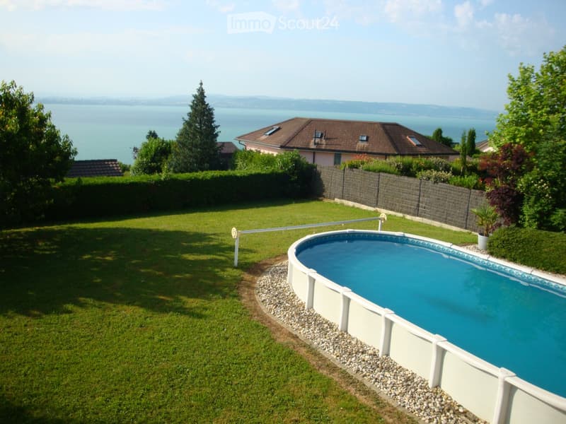 oval shaped swimming pool, green lawn, gravel border, trees, bushes, view of the sea
