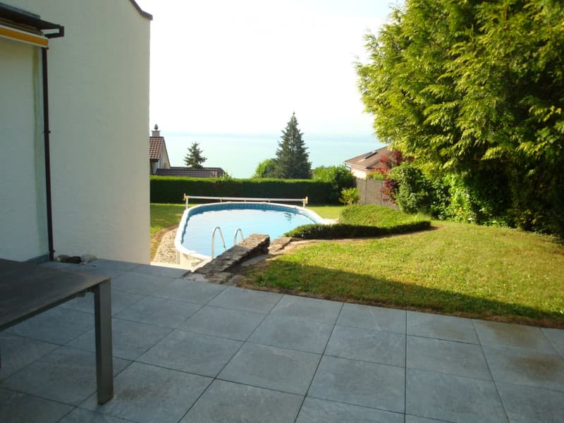 Swimming pool, grassy lawn, hedges, trees, table, view of the sea