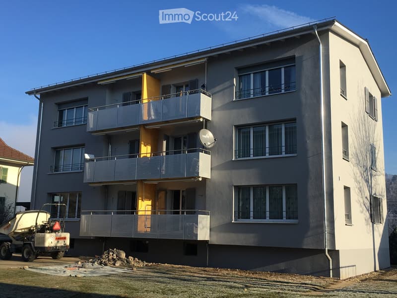 3 story apartment building, gray exterior, balconies, windows, satellite dish