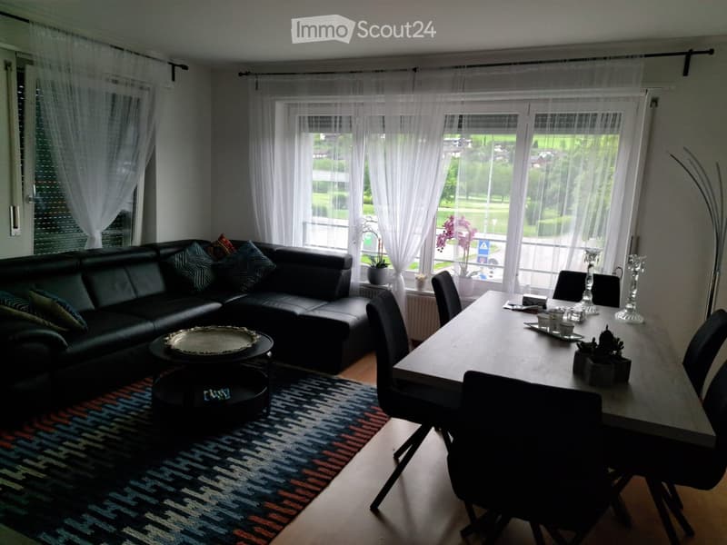 black leather sofa, coffee table, dining table with chairs, large windows, white curtains, rug, plants