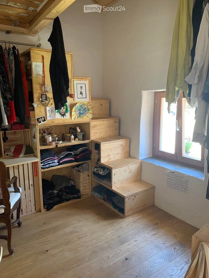room with wooden shelves, wooden steps, clothes hanging, window