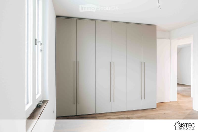 Minimalist room with white built-in wardrobes, wooden floor, large window with a wooden sill
