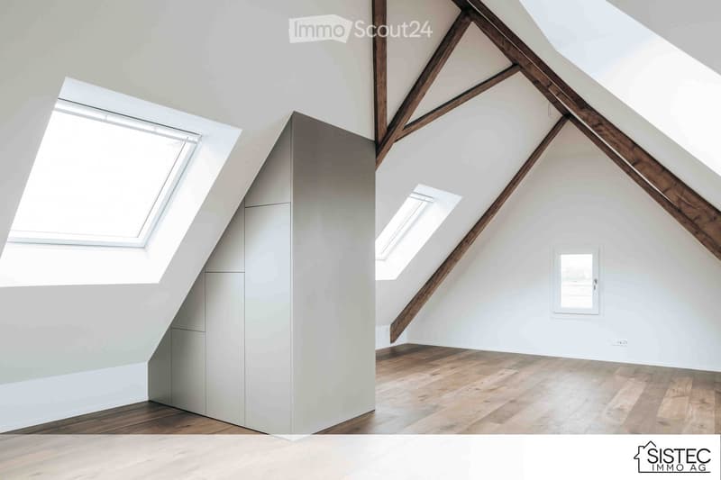 Empty attic space with wooden beams, wooden floor, built-in closet, two dormer windows, small window