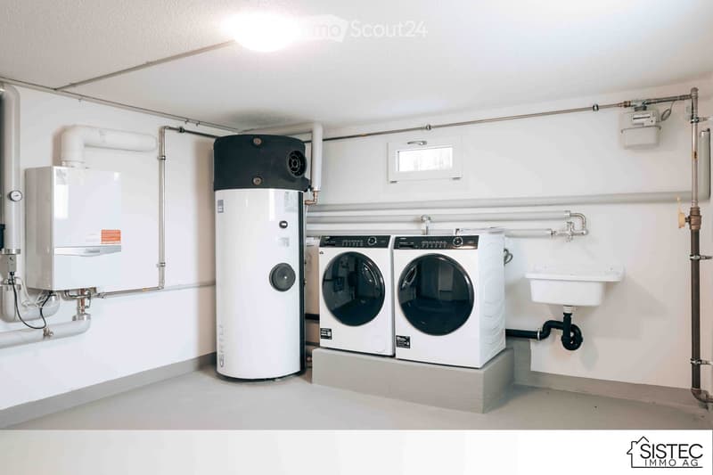 Laundry room with two washers, a sink, and water heater