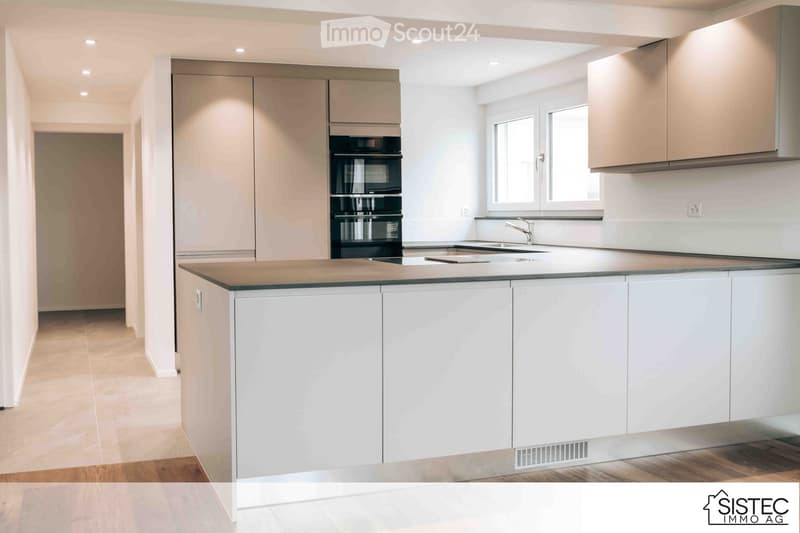 Modern kitchen, white cabinets, gray countertops, stainless steel oven, sink, faucet, and a window with a view.