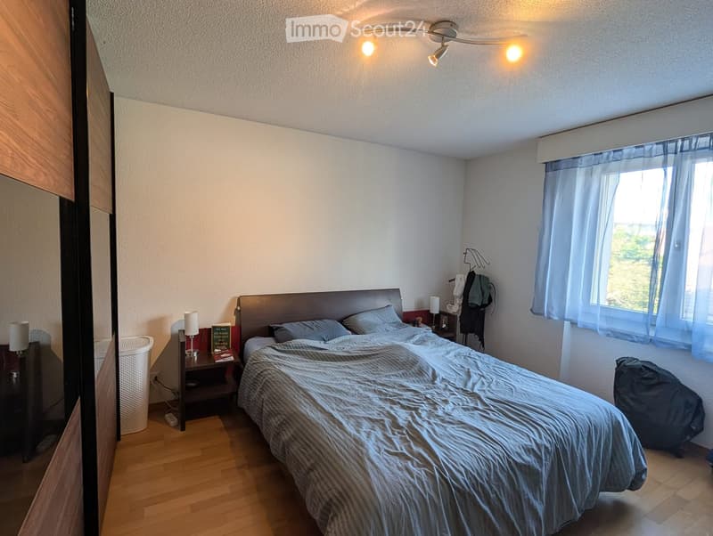 Bedroom. Bedroom with a double bed, nightstand, lamp, mirror, and wardrobe. Light blue curtains cover the window, and the room has wooden flooring.