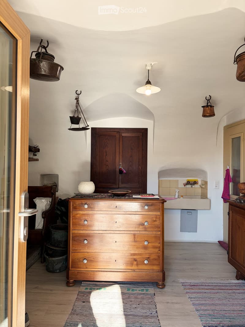 A room with a wooden cabinet, sink, and an antique lamp.