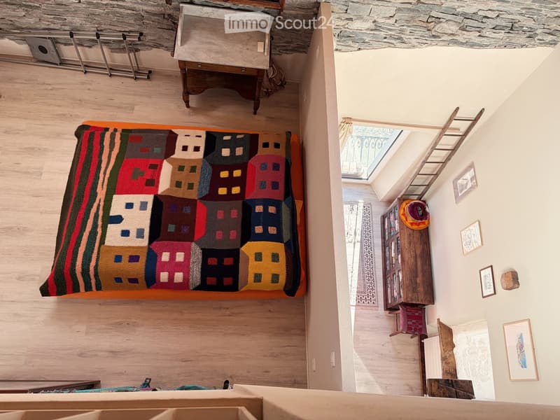 Raised ground floor, wooden floor, wall-mounted art, ladder, wooden furniture, skylight, rug, and decorative items