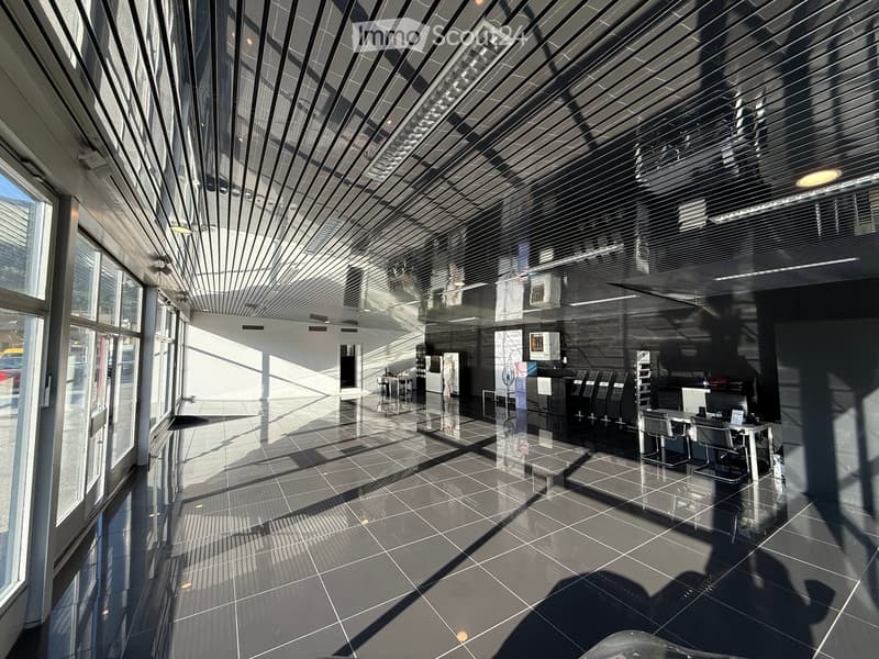 Furnished Room. Modern, spacious lobby area with large windows, sleek furniture, and a polished tile floor.