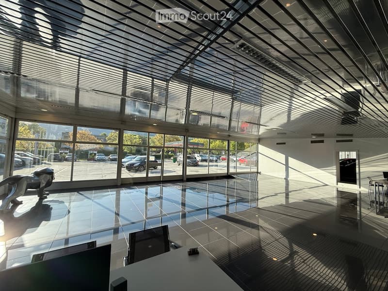Furnished Room. Modern, spacious interior with a sleek, reflective floor, large glass windows, and a contemporary sculpture. The area includes a desk with a computer and chairs.