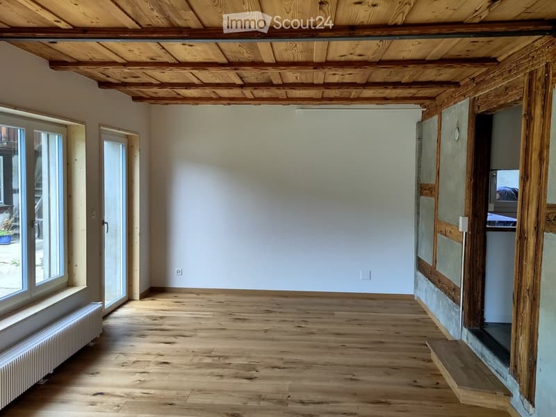 Unfurnished Room. Empty room with wooden ceiling, white walls, wooden floor, and a window with a view of a garden.