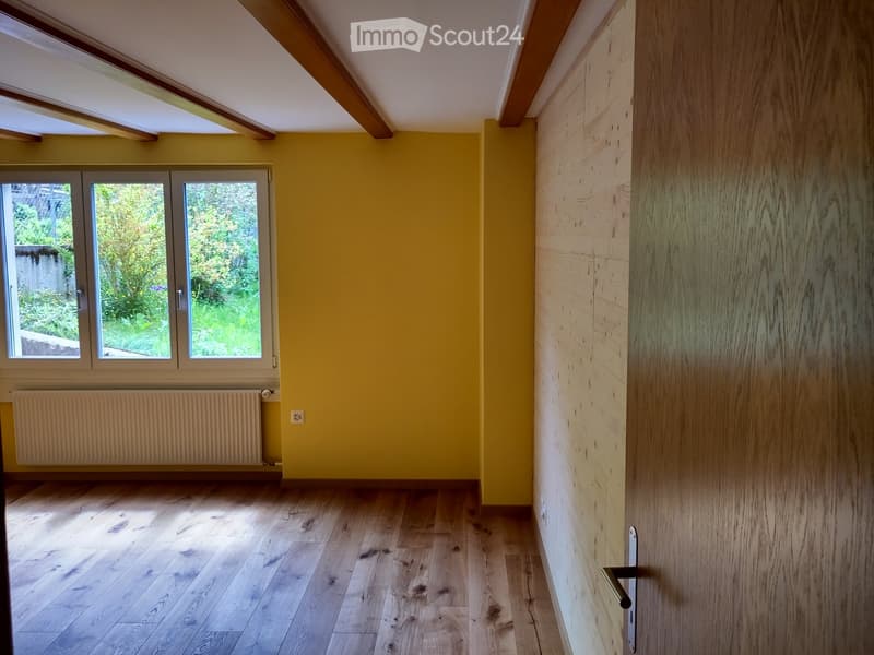 Unfurnished Room. Empty room with wooden floor, yellow walls, white ceiling, and a window with a view of a garden.