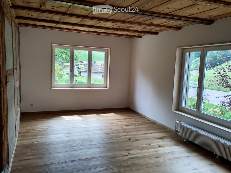 Unfurnished Room. Empty room with wooden floor, white walls, wooden ceiling, two windows, and a radiator.