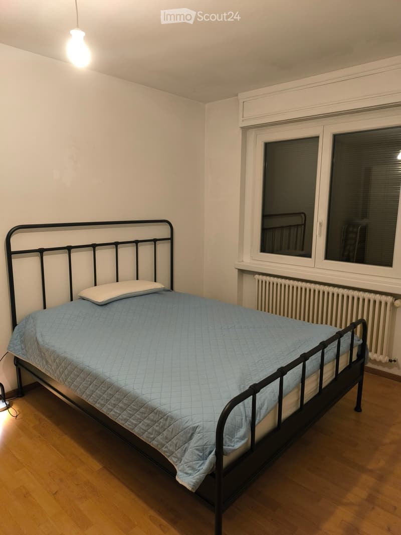 Bedroom. A small bedroom with a single bed, light blue bedding, a radiator, and a window with blinds.