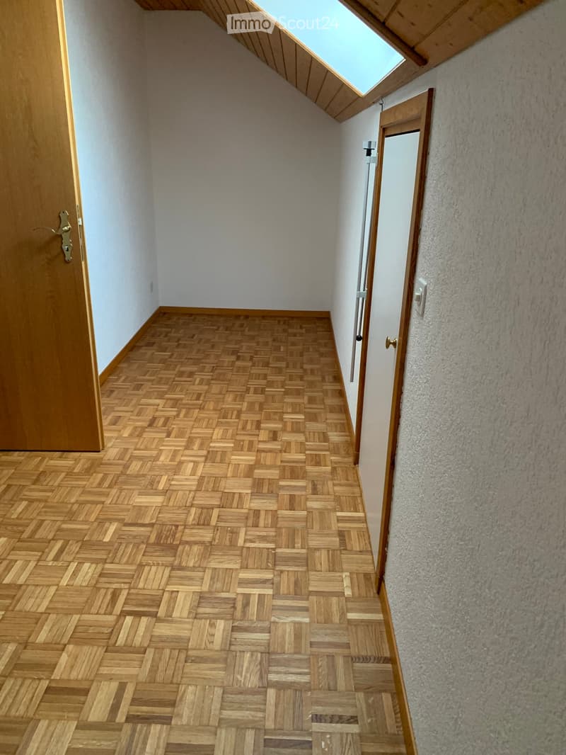 Corridor / Hallway. A narrow hallway with wooden herringbone flooring, white walls, and a skylight at the top. Two wooden doors are visible on either side.