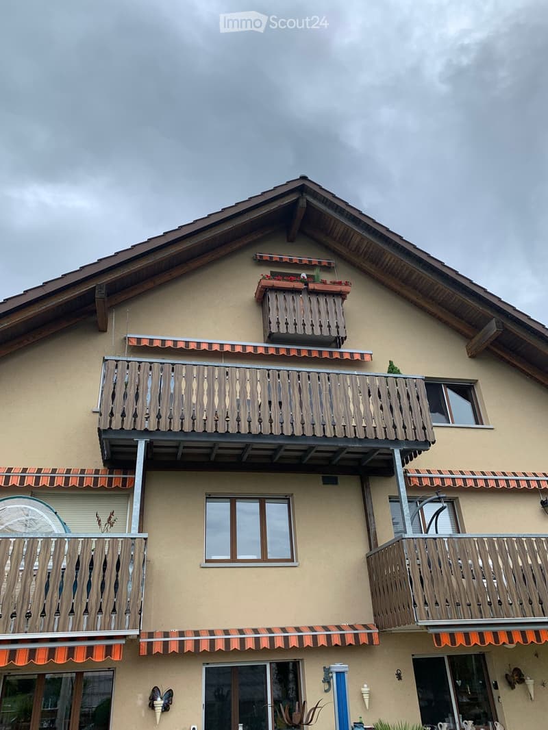 Building. Two-story house with multiple balconies, wooden railings, and decorative flower boxes on the roof.