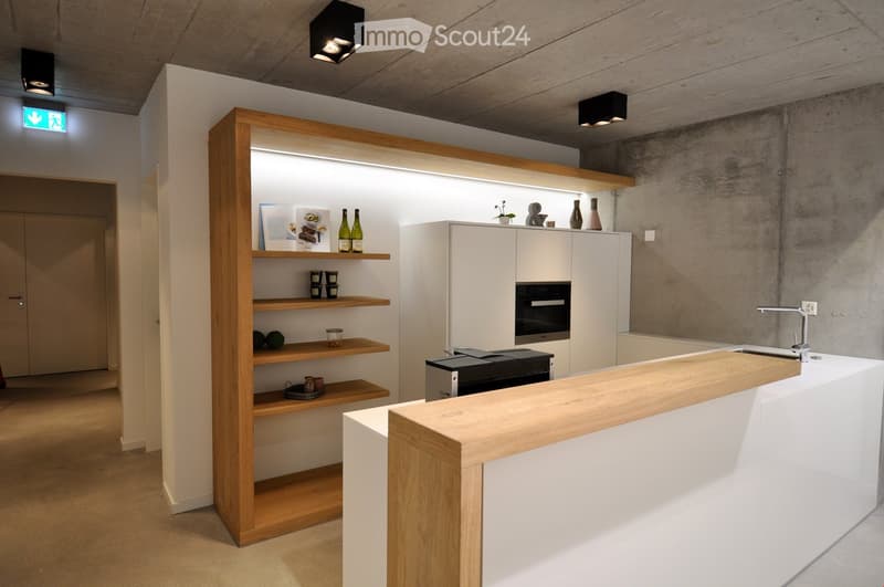 Kitchen. Modern kitchen with white cabinets, wooden shelves, and a central island. Features an oven, sink, and decorative items on shelves.