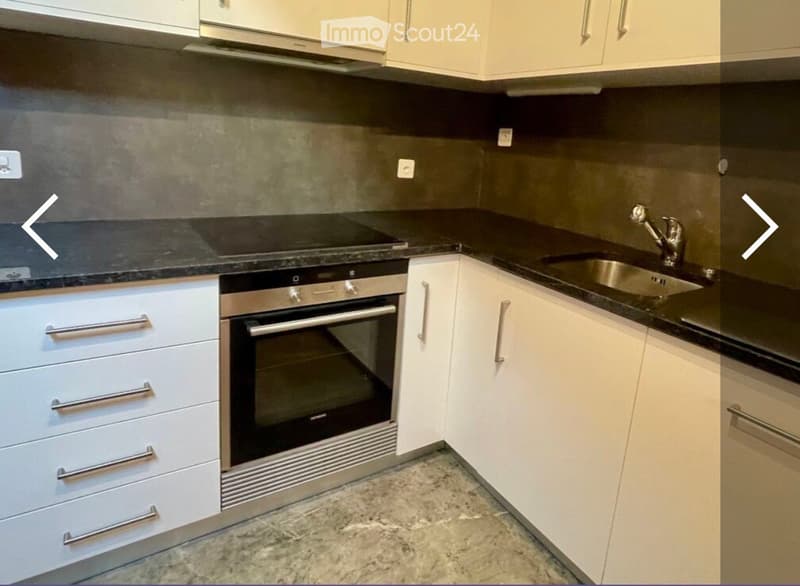 Kitchen. Modern kitchen with white cabinets, black countertops, stainless steel oven, and sink.