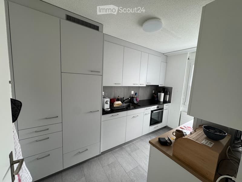 Kitchen. Modern kitchen with white cabinets, stainless steel appliances, and a wooden island with a cup and bowl on top.